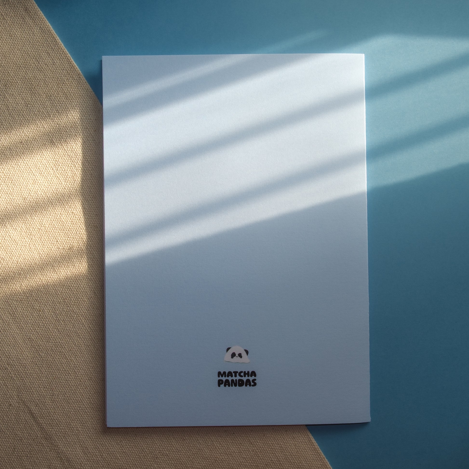 Back of light blue greeting card - Matcha Pandas logo and melting panda popsicle