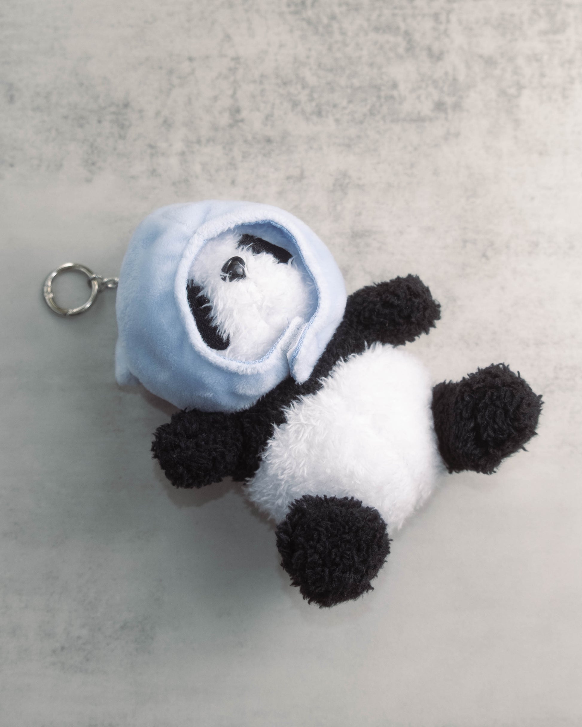 Kawaii panda plush keychain wearing a blue bear hat keychain displayed on a clean background, showing its fluffy texture and compact size for everyday carry.