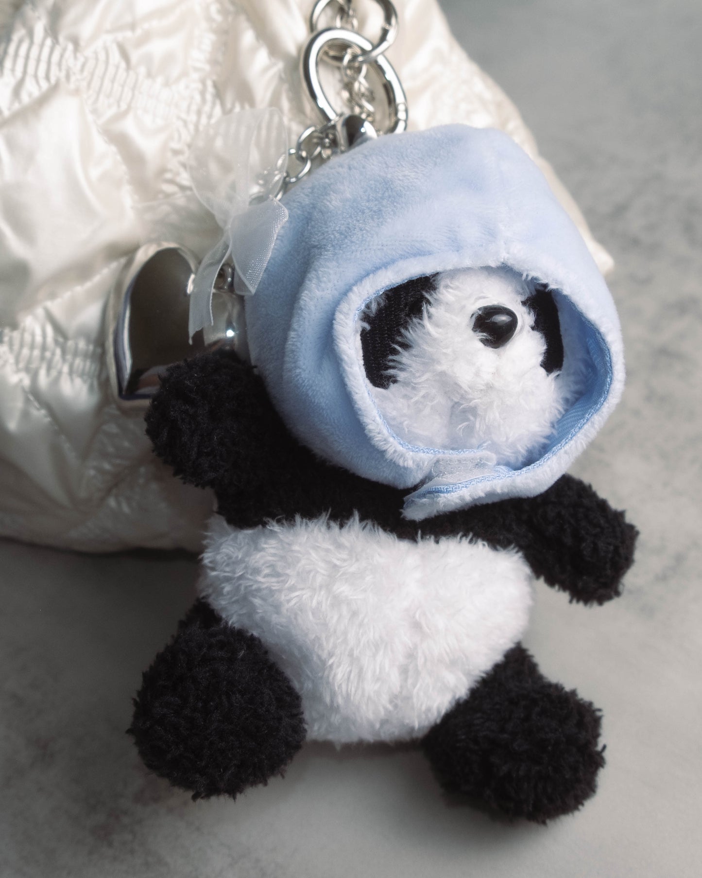 Cute panda plush keychain hanging from a purse zipper, adding a soft and adorable accessory to everyday bags.