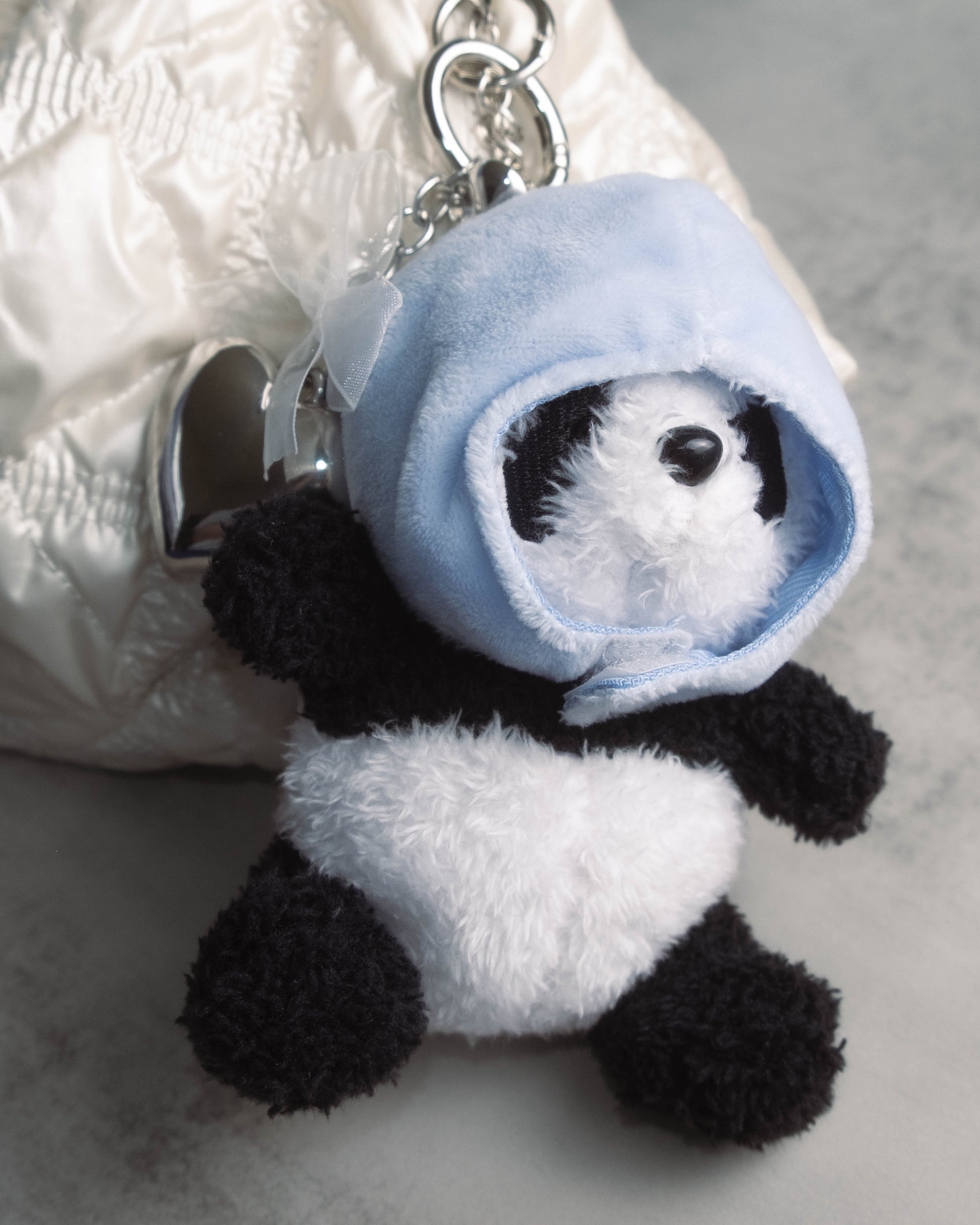 Cute panda plush keychain hanging from a purse zipper, adding a soft and adorable accessory to everyday bags.