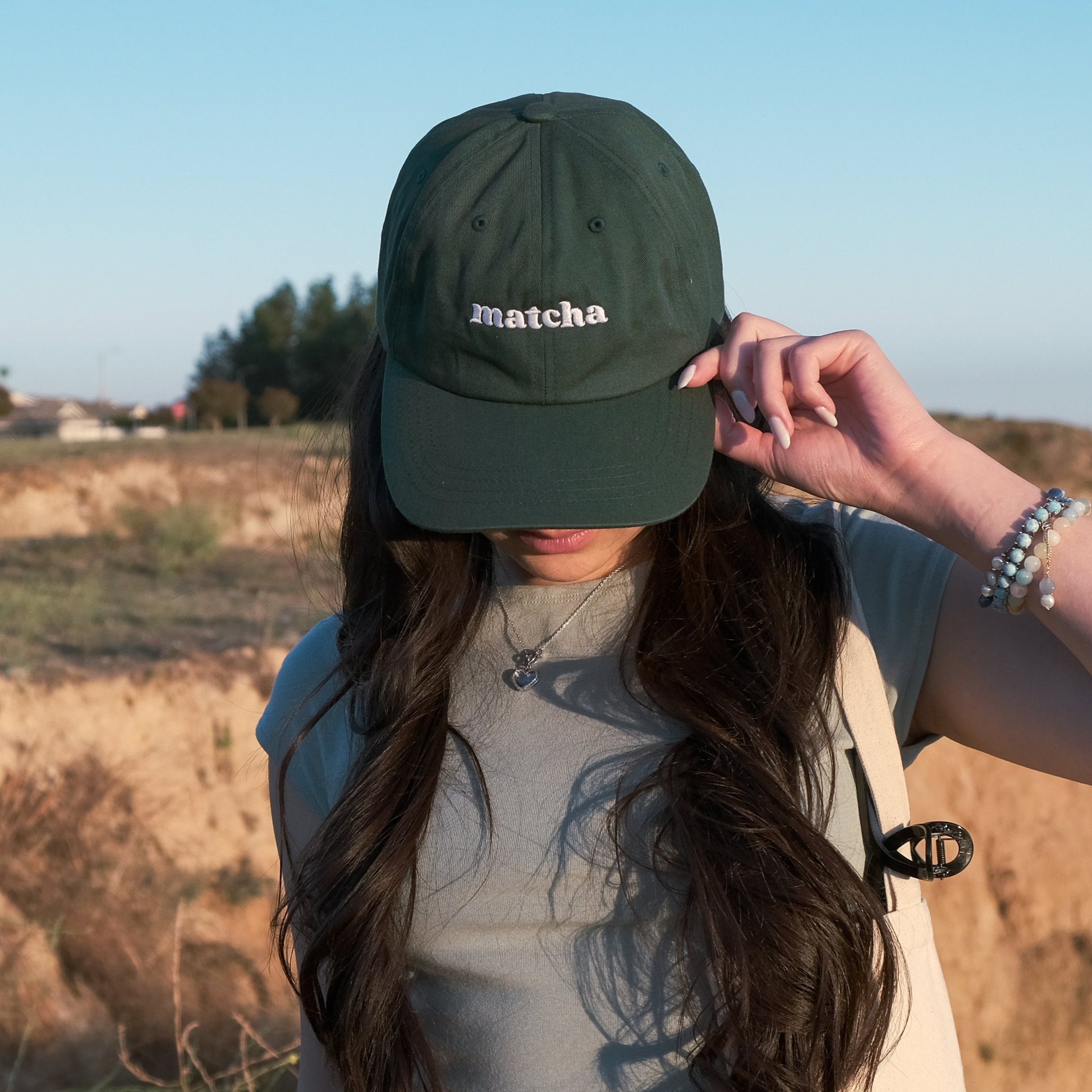 Model wears a green baseball cap with white embroidered text, "matcha"