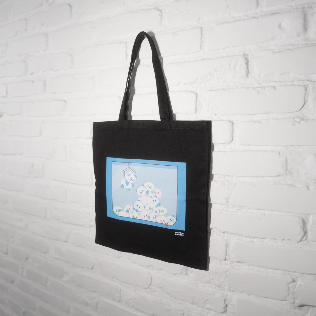 Black canvas tote bag with pastel pandas in a claw machine
