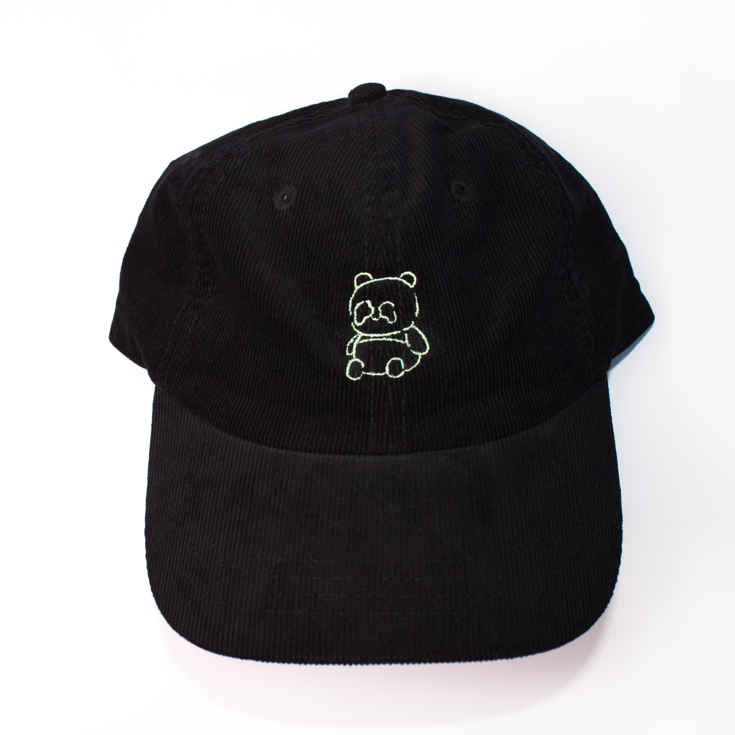 A black baseball cap made of textured corduroy fabric, featuring a small green embroidered panda bear on the front, set against a plain white background.