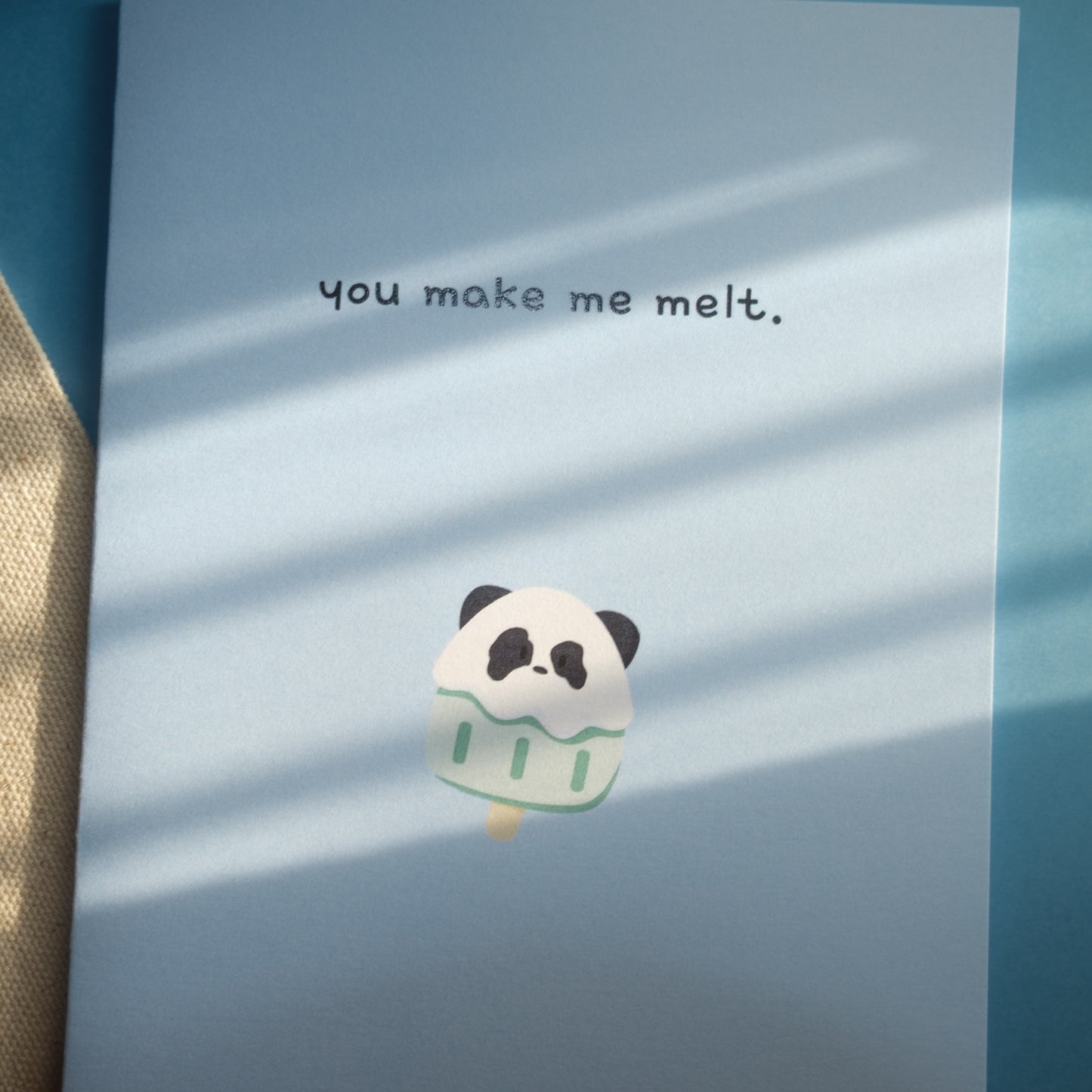 Light blue greeting card  of a panda popsicle with the text, "you make me melt."