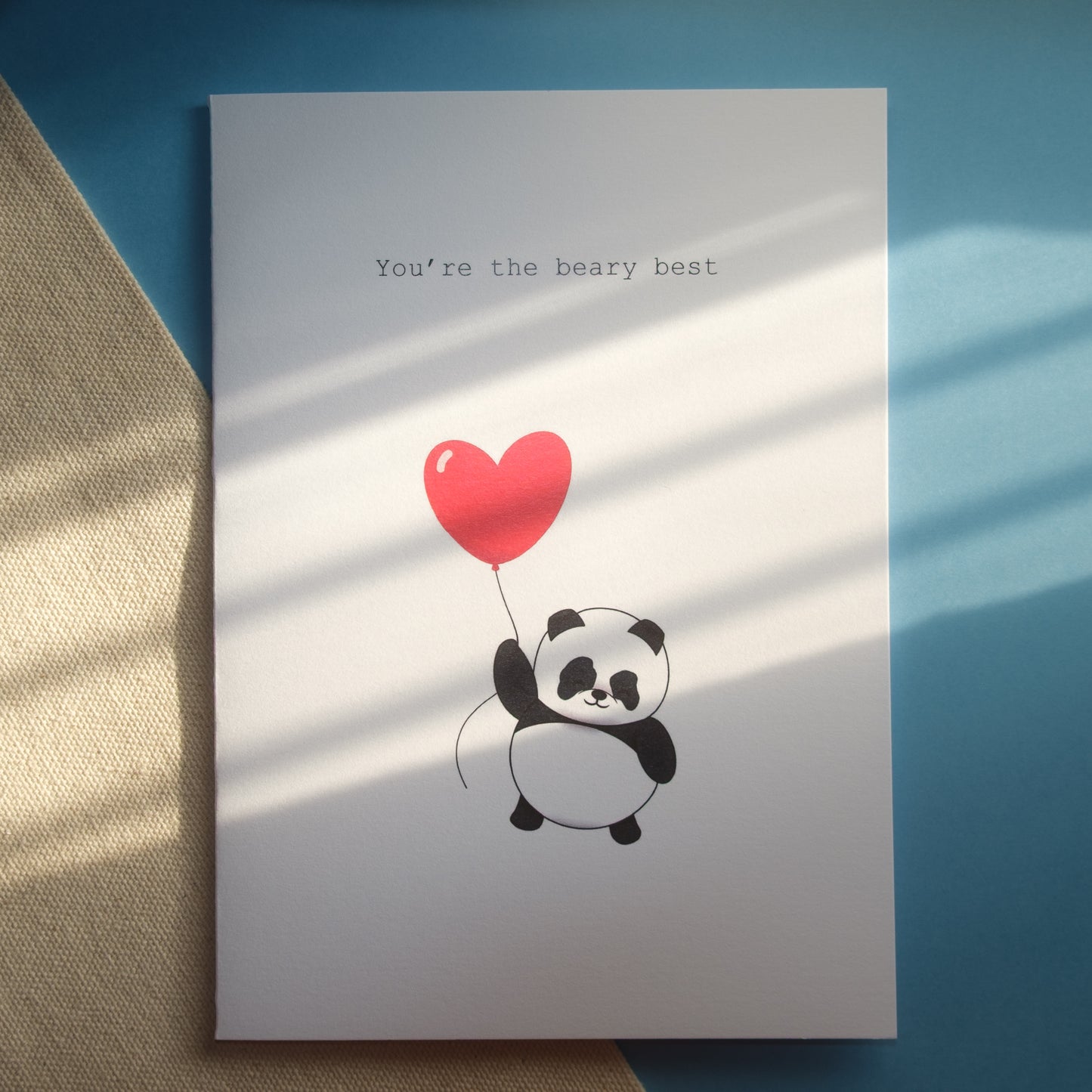 Greeting card with a floating panda holding a red heart balloon and text 'You're the beary best' 
